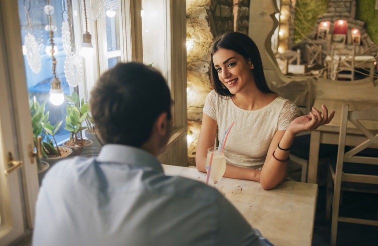 Portrait of smiling young woman talking to her boyfriend in a restaurant